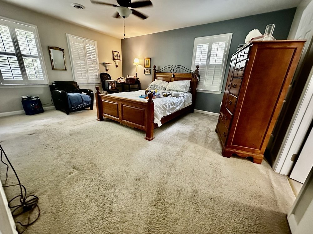 Master bedroom with worn beige carpet before hardwood installation