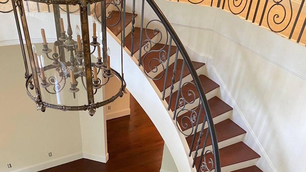 Refinished curved staircase with dark stained treads and iron balusters in a Raleigh home