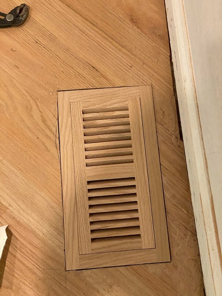 Wood floor register cut flush into a refinished oak floor so the grain lines up