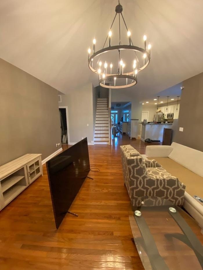 Refinished hardwood floor running through an open plan living room and kitchen in Apex