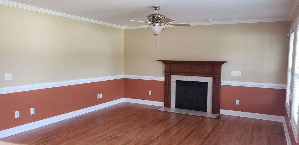 Freshly refinished hardwood floor in an empty formal living room with a fireplace