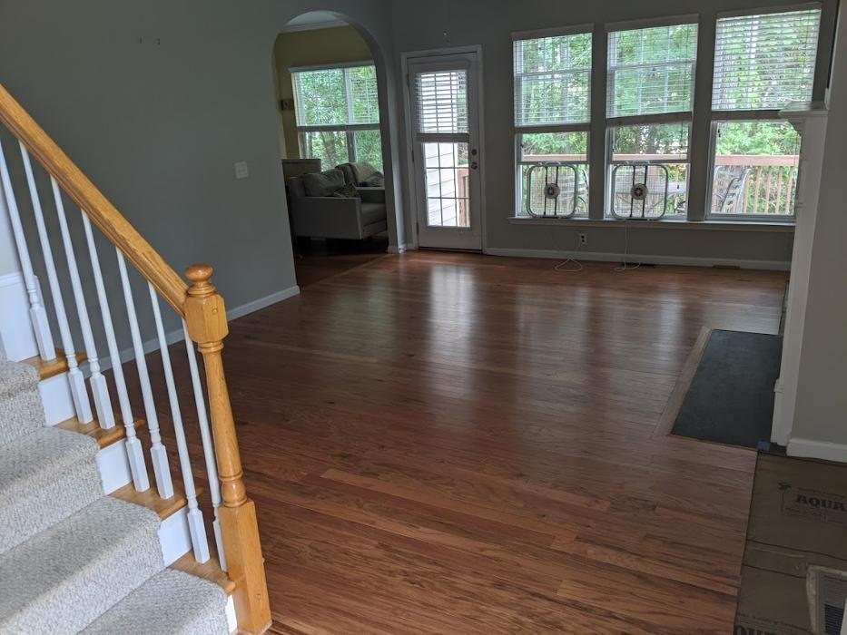 Refinished honey oak floor in a Raleigh living room with a white balustrade